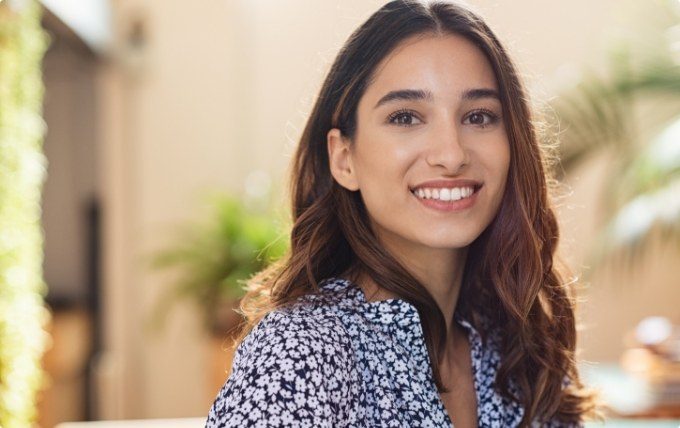 Woman in black and white flowery blouse smiling outdoors