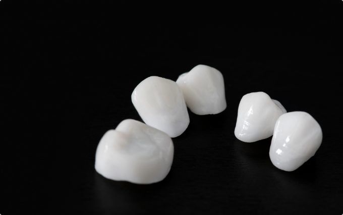 Several white dental crowns against black background