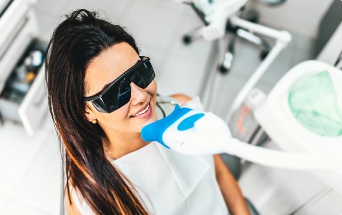 Woman receiving professional teeth whitening in dental office