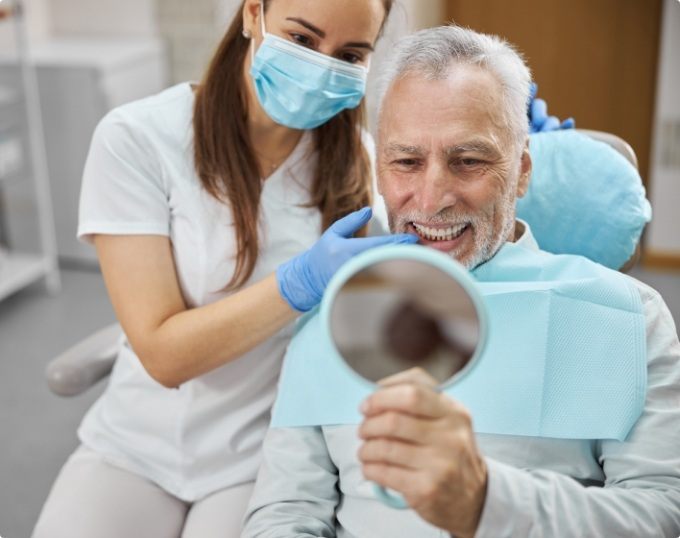 Senior dental patient looking at his smile in mirror