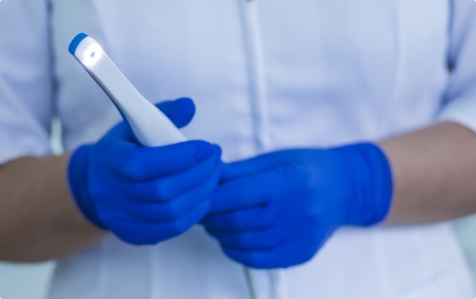 Two gloved hands holding an intraoral camera