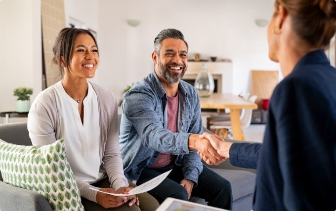 Man shaking hands with person sitting in chair across from him