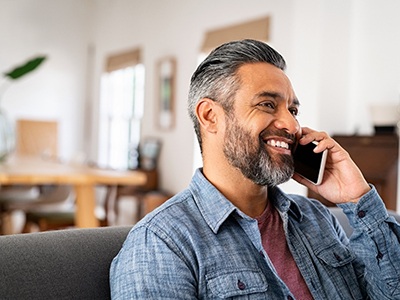 Man smiling while talking on phone at home