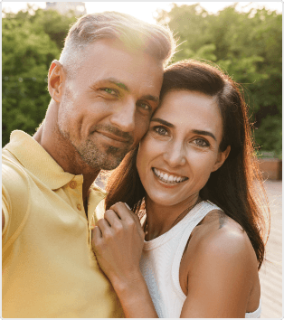 Man and woman grinning outdoors