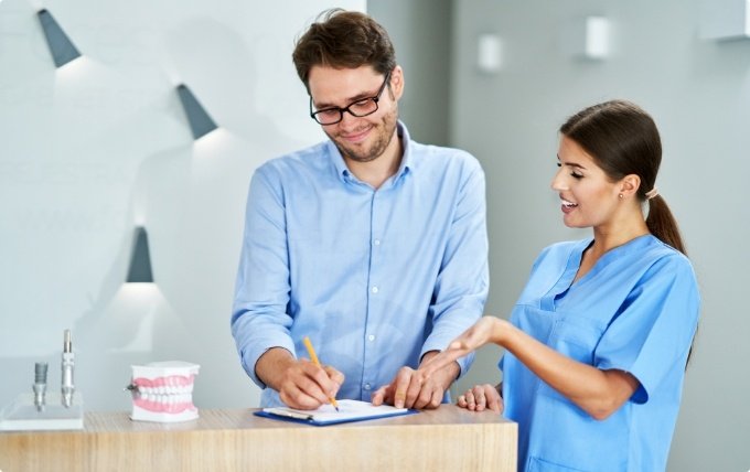 Dental team member showing a patient where to sign on clipboard