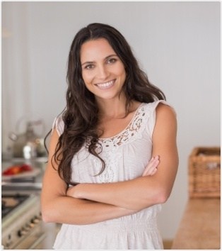 Woman standing and smiling with arms crossed after receiving dental services in Moorestown