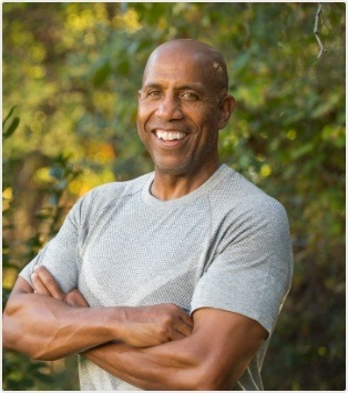 Older man smiling with trees in background