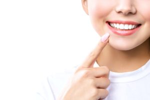 Nose to chin view of woman with pink nails pointing to her smile